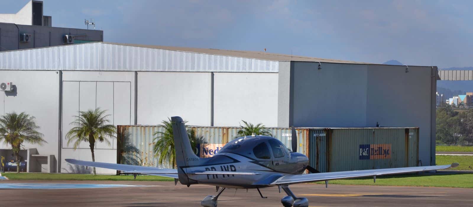 A single-engine aircraft parked on the ramp in front of the hangars