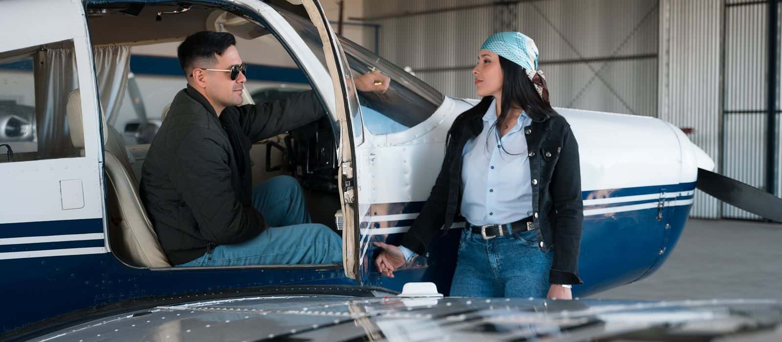 An instructor and a student talking beside a light aircraft in a hangar